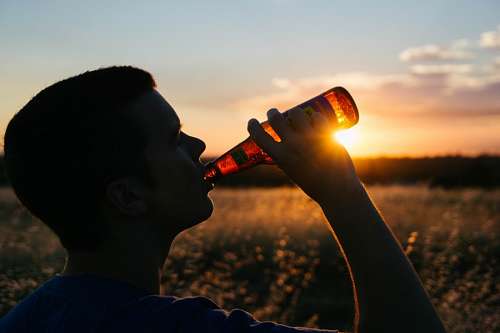 Homem, tendo, um, soda, em, pôr do sol